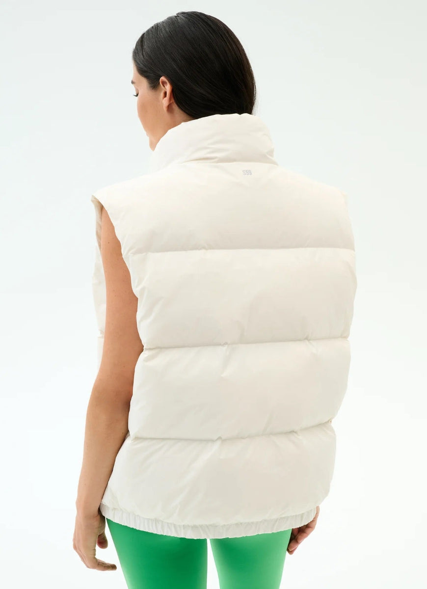 Person wearing a white puffer vest on a light gray background