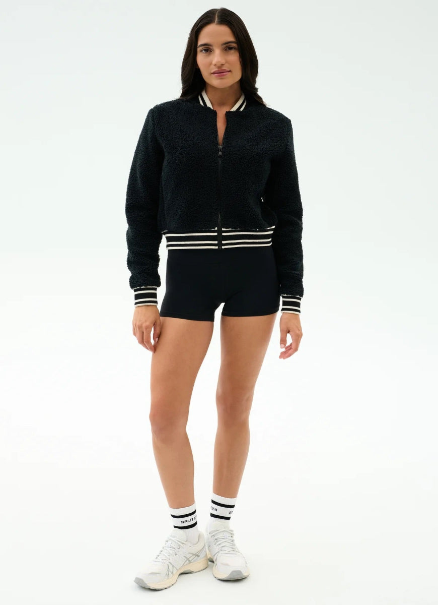 Woman wearing a black tracksuit with white accents on a white background