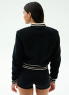 Person wearing a black sweater with white stripes on a plain background
