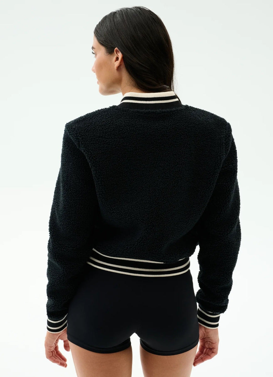 Person wearing a black sweater with white stripes on a plain background
