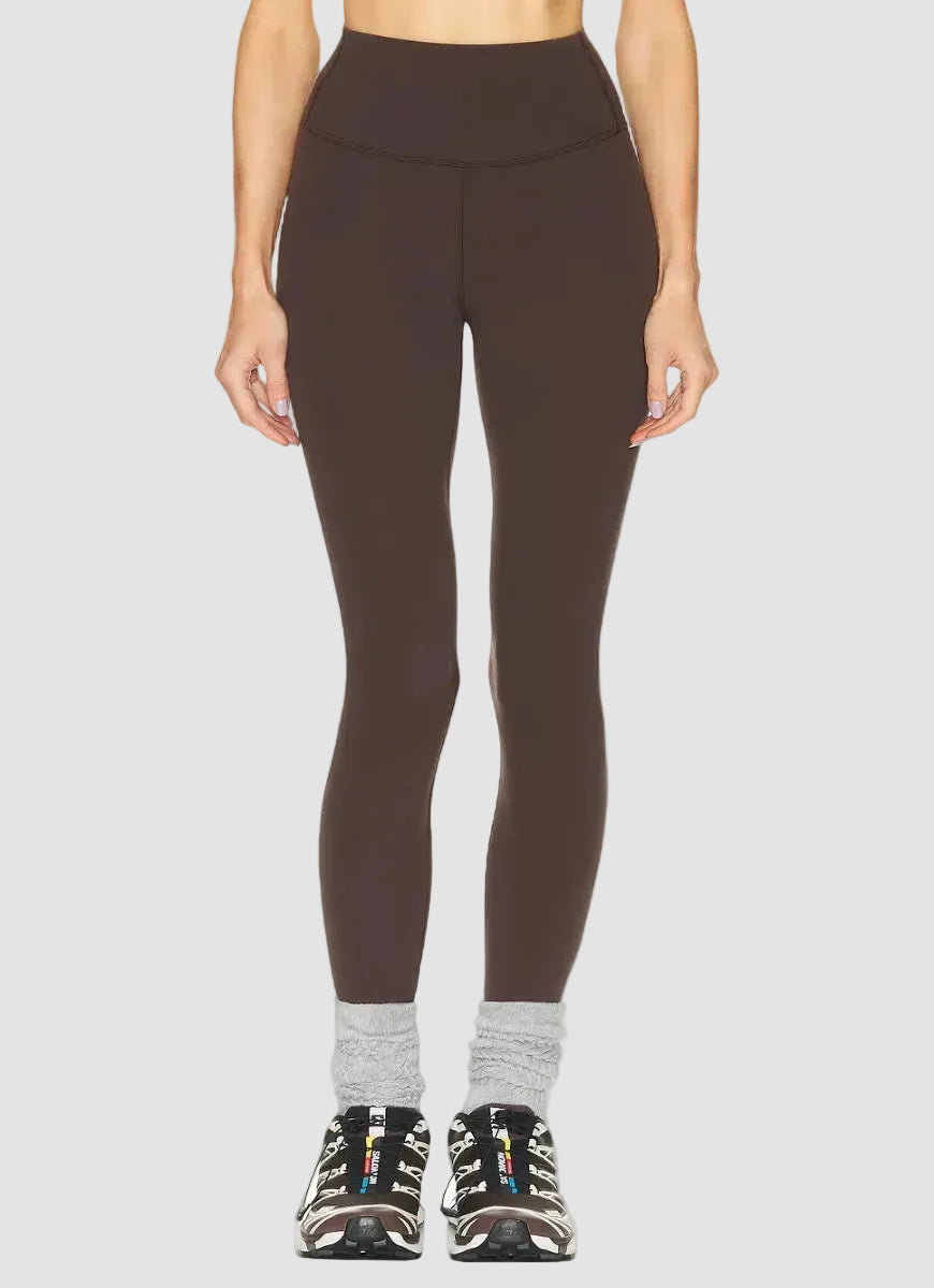 Person wearing brown leggings on a white background