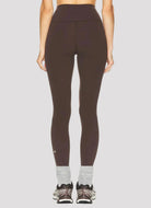 Person wearing brown leggings on a white background