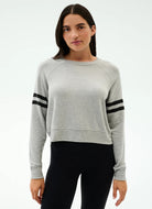 Woman wearing a gray sweatshirt with black stripes on a white background