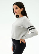 Woman wearing a gray sweater with black accents on a white background