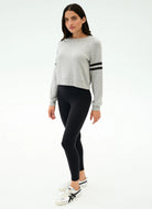 Woman wearing a gray sweater with black leggings on a white background