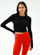 Woman wearing a black long-sleeve top and red leggings on a white background