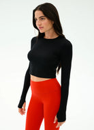 Woman wearing a black long-sleeve top and red leggings on a white background