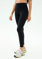 Person wearing black leggings with white sneakers on a white background