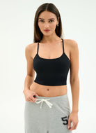 Woman wearing a black sports bra and gray sweatpants on a white background