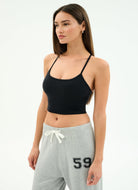 Woman wearing a black sports bra and gray sweatpants with '59' on a white background