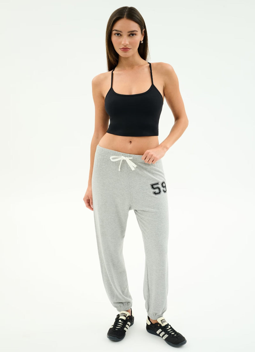 Woman wearing a black sports bra and gray sweatpants with '59' on a white background