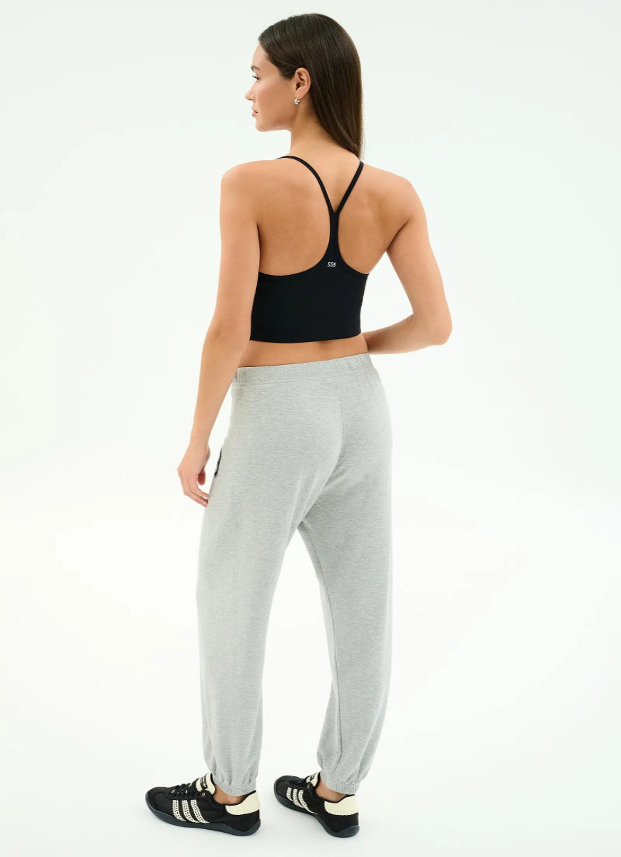 Woman wearing a black sports bra and gray jogger pants on a white background