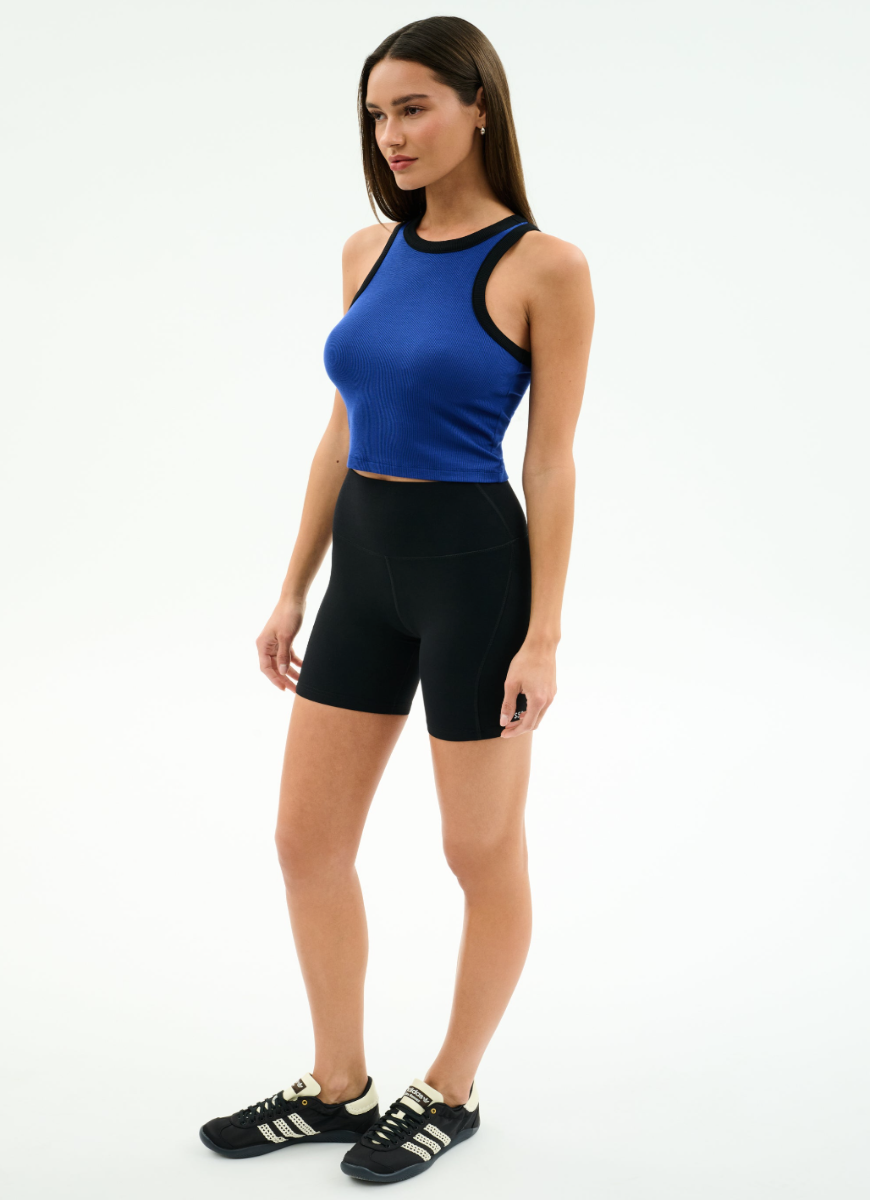 Woman wearing a blue tank top and black shorts on a white background