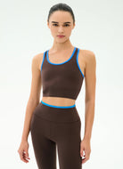 Woman wearing a brown sports bra and leggings with blue accents on a white background
