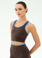Woman wearing a brown sports bra with blue trim on a white background