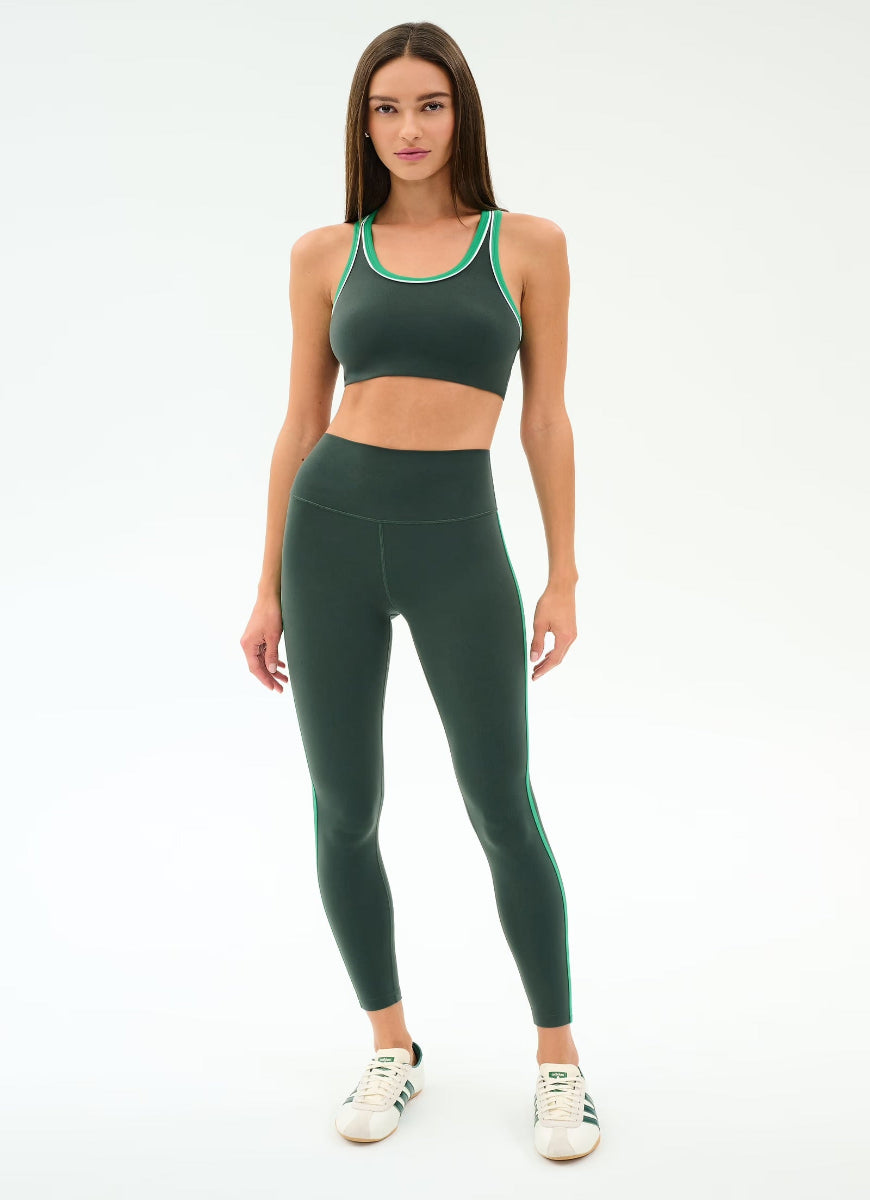 Woman wearing a green sports bra and leggings set on a white background