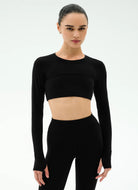 Woman wearing a black long-sleeve crop top and leggings on a white background