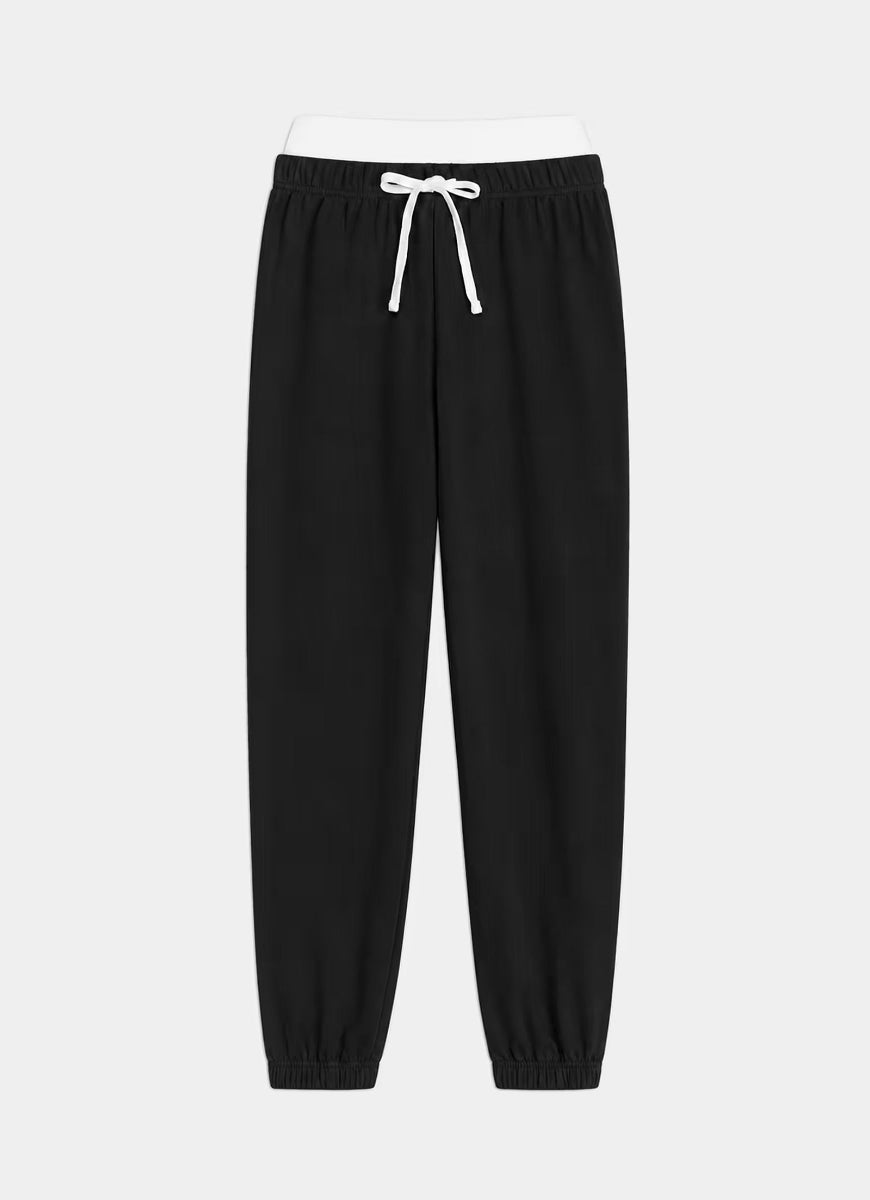 Black jogger pants with an elastic waistband, white drawstring, and elastic cuffs, shown against a light gray background.