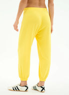 Yellow sweatpants worn by a person on a white background