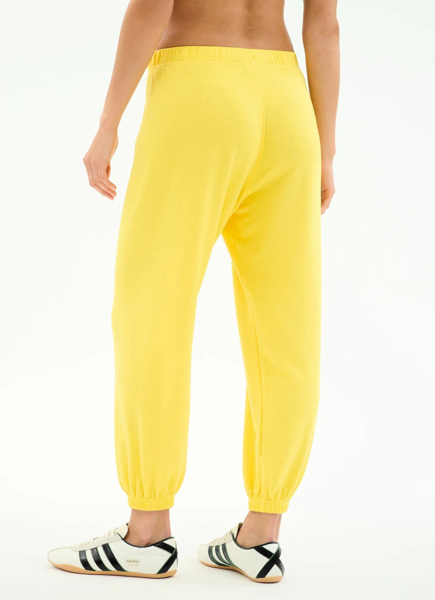 Yellow sweatpants worn by a person on a white background