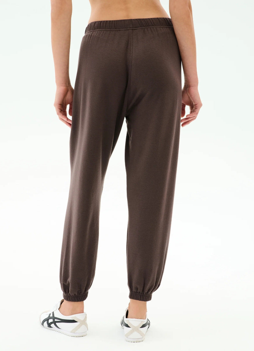 Brown jogger pants worn by a person on a white background