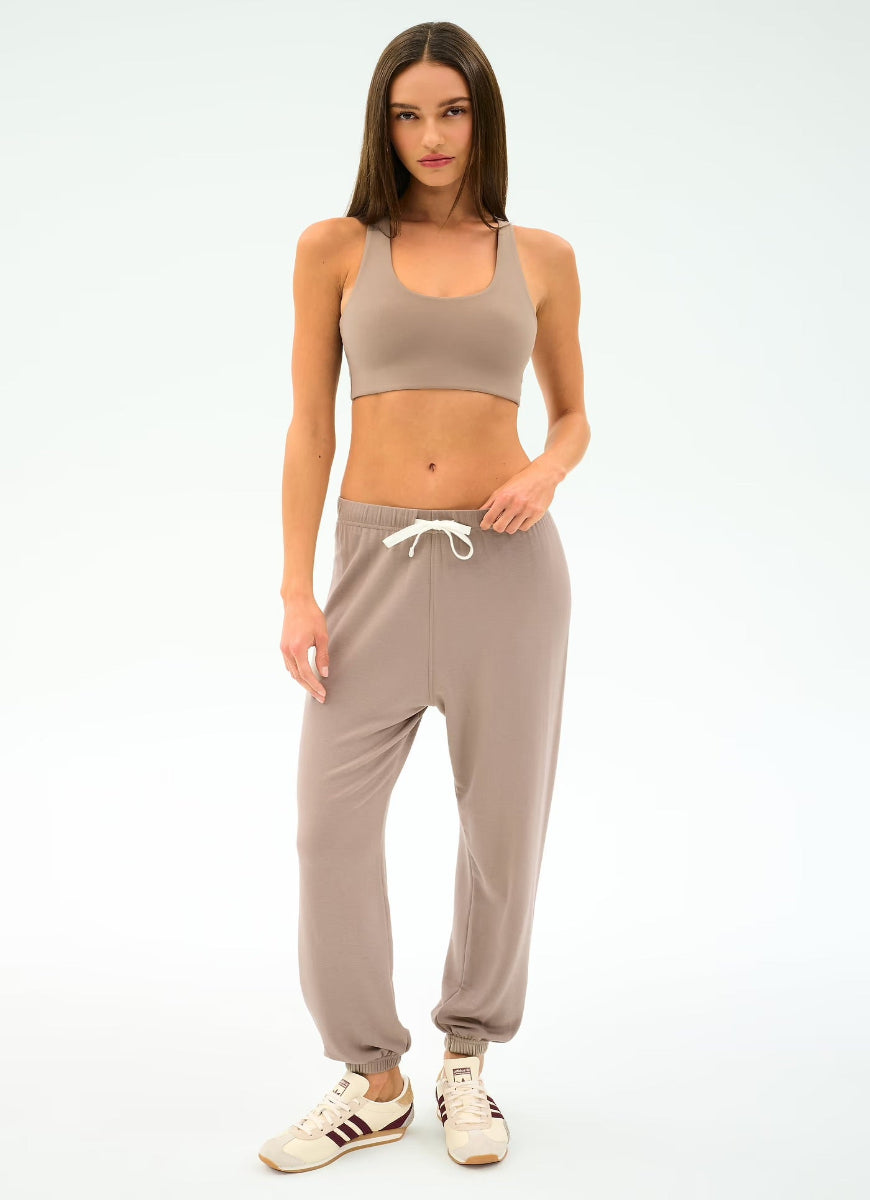 Woman wearing a beige sports bra and jogger pants on a white background