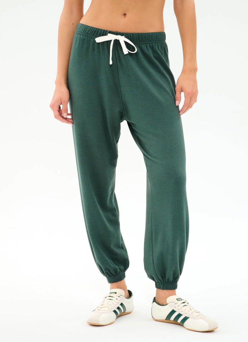 Green sweatpants worn by a person on a white background