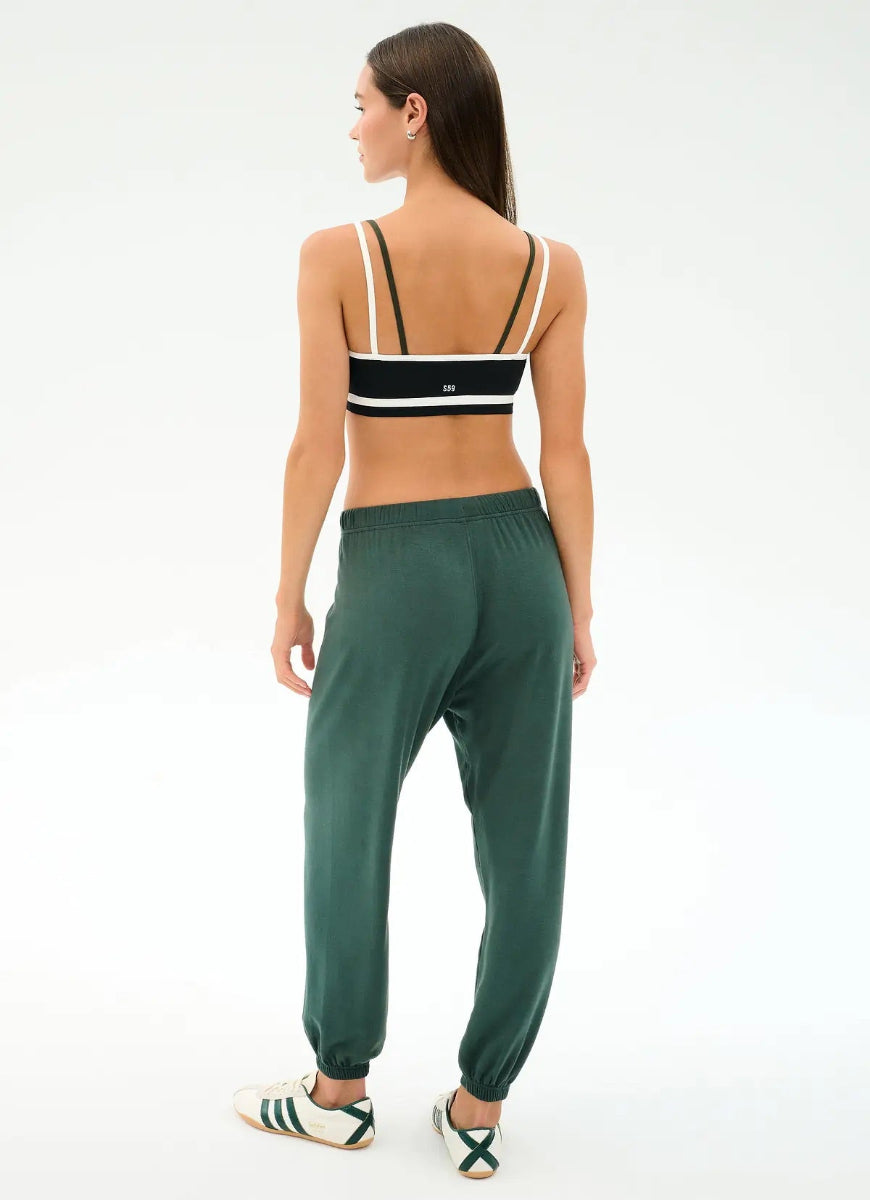 Woman wearing a black and white top and green pants on a white background