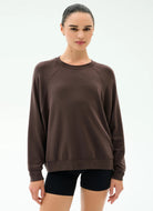 Woman wearing a brown sweatshirt and black shorts on a white background