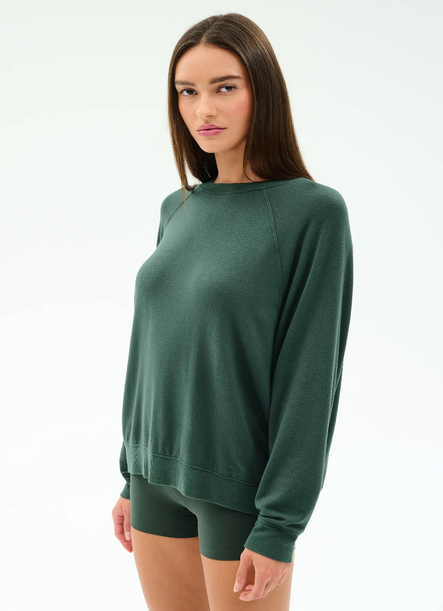 Woman wearing a green sweatshirt and shorts on a white background