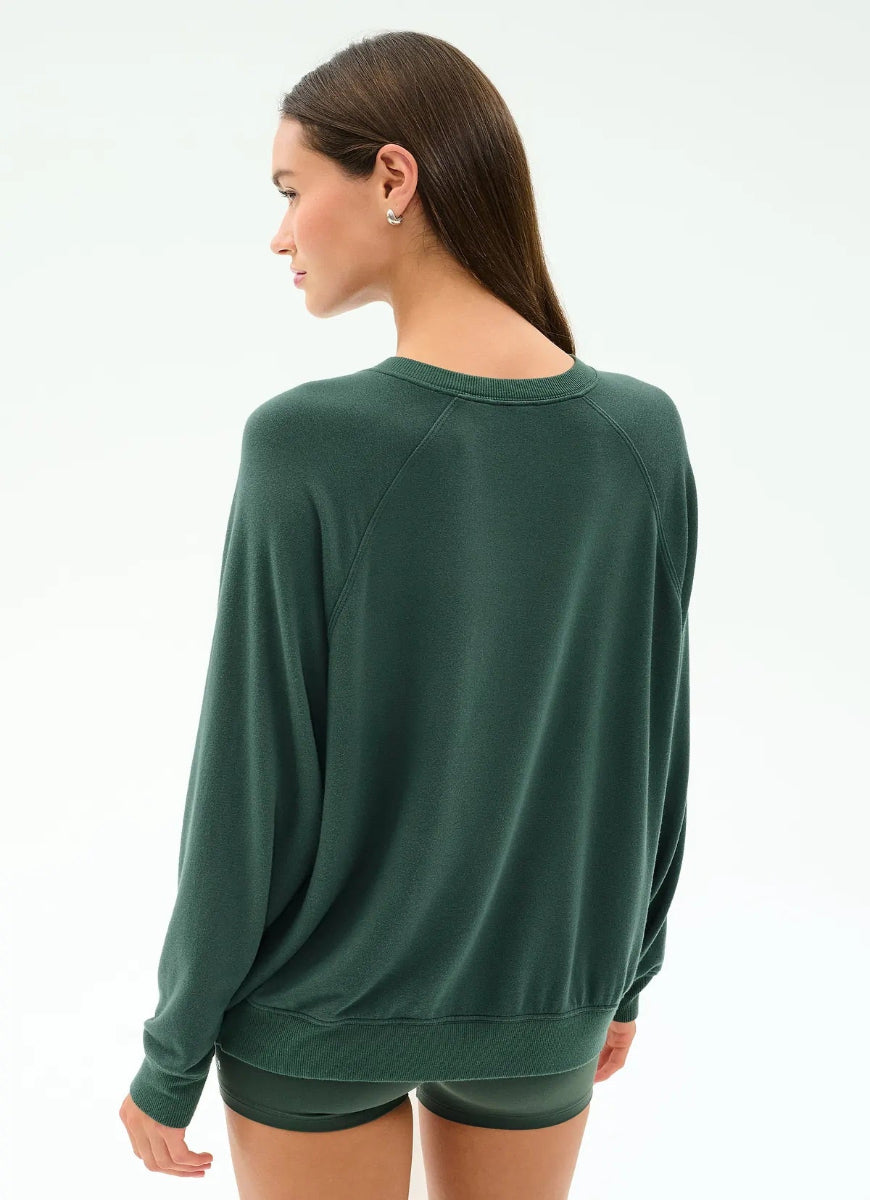 Woman wearing a green long-sleeve top and shorts on a white background