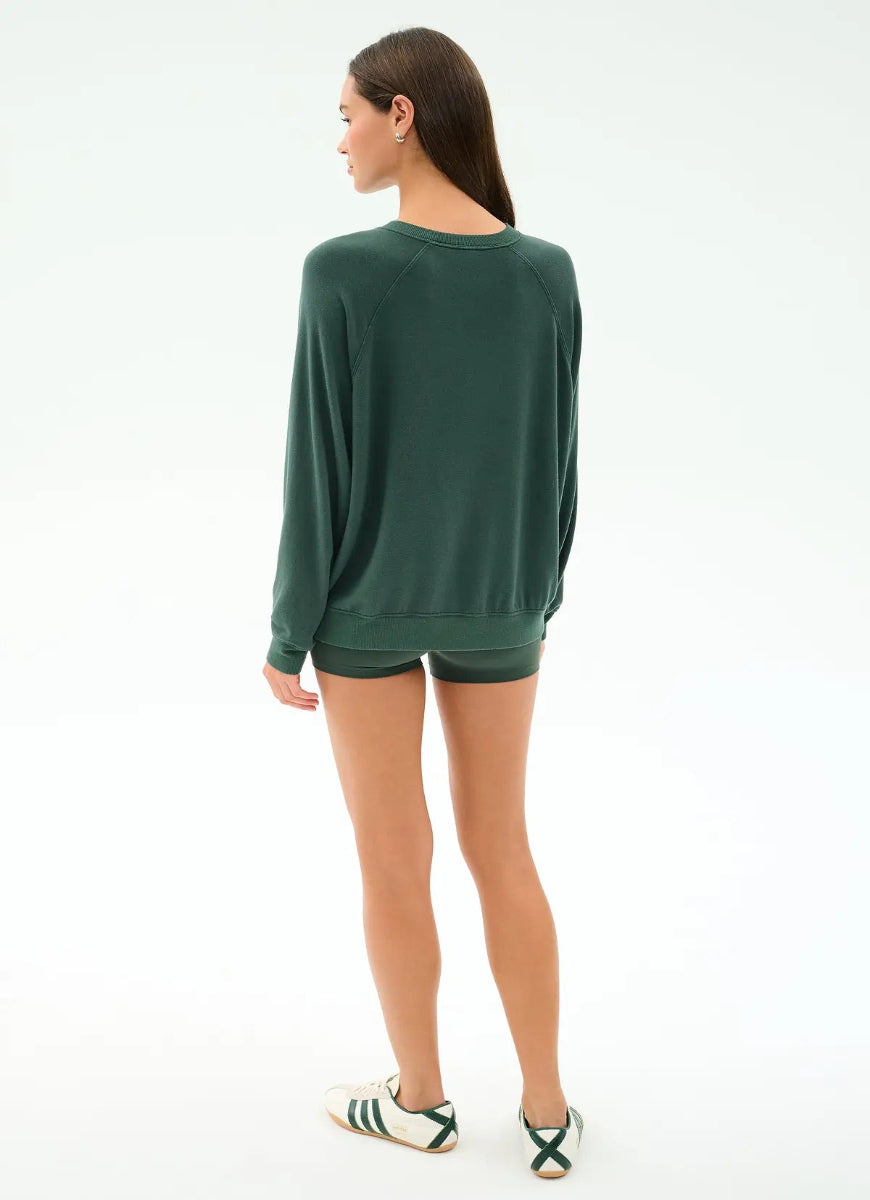 Woman wearing a green sweatshirt and shorts on a white background