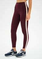 Maroon leggings with a white stripe worn by a person on a white background