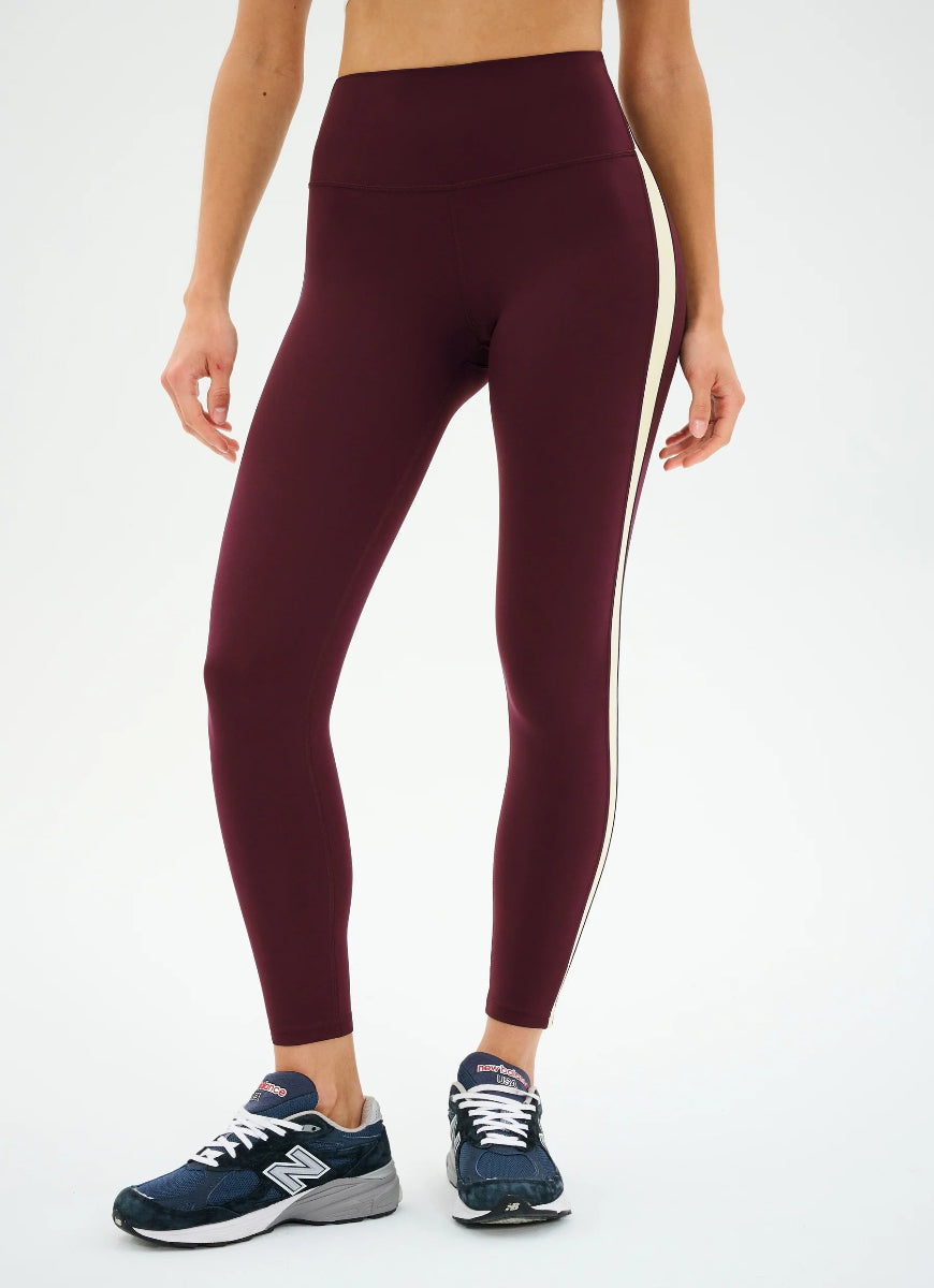 Maroon leggings with white stripes worn by a person on a white background