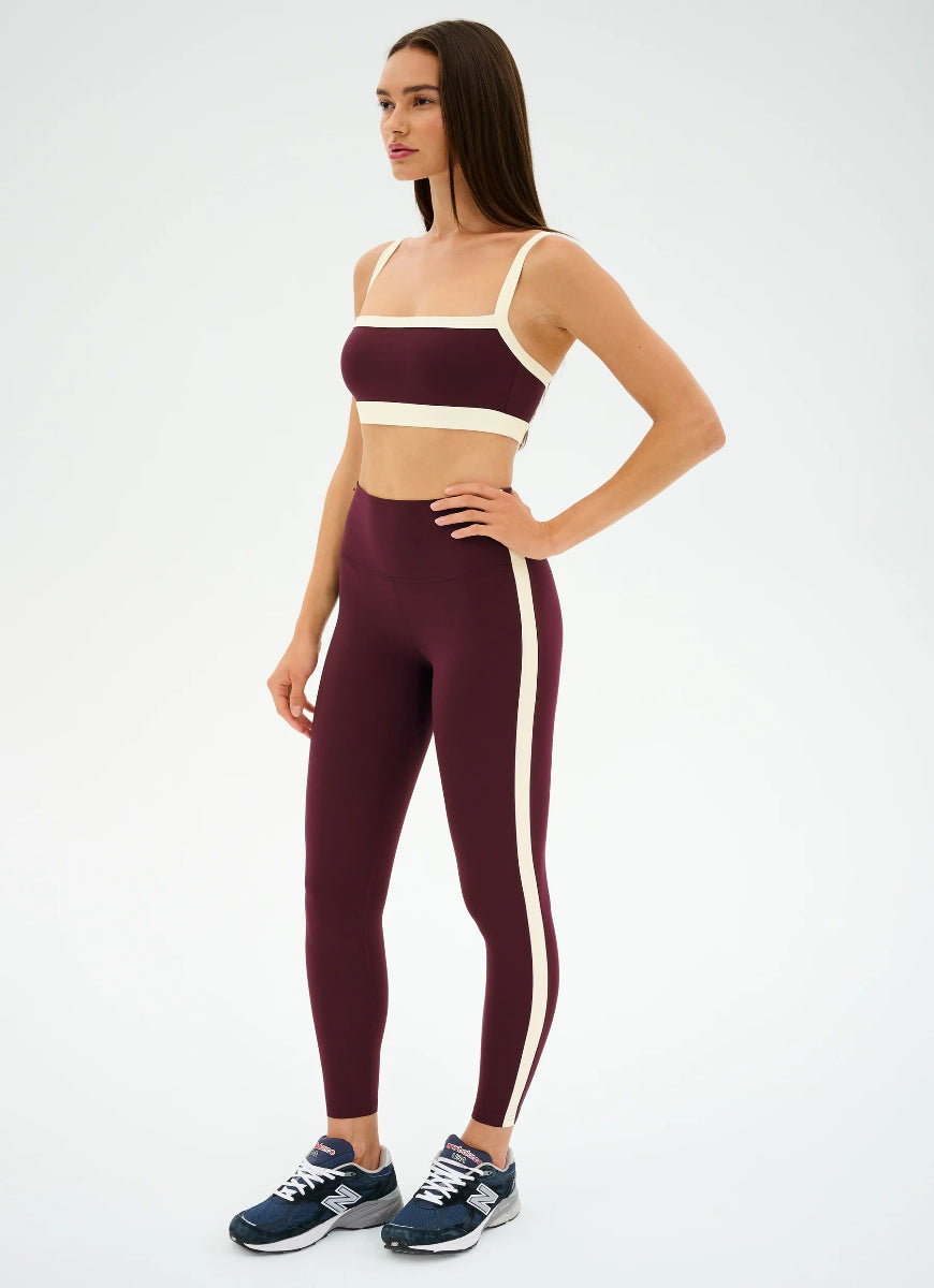 Woman wearing a burgundy and white sports outfit on a white background