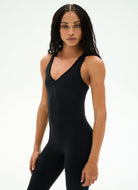 A woman modeling a black sleeveless bodysuit with a deep V-neckline against a plain white studio background.