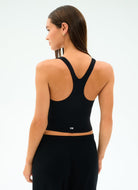 Woman wearing a black sports bra and leggings on a white background