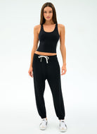 Woman wearing a black athletic outfit with white sneakers on a white background