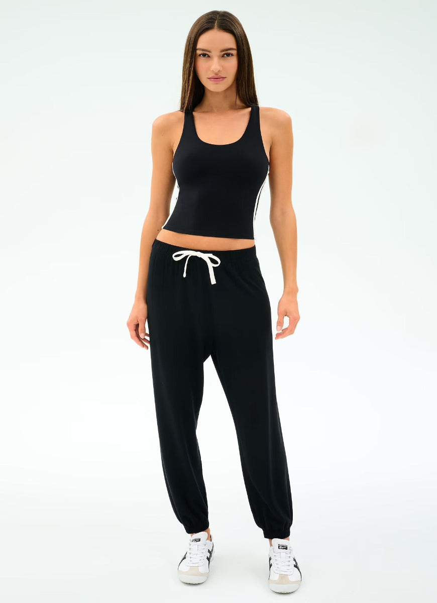 Woman wearing a black athletic outfit with white sneakers on a white background