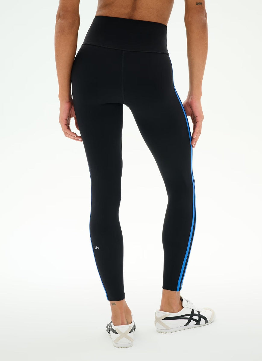 Black high-waisted leggings with a bright blue side stripe and a small white logo near the ankle, shown on a model from the back against a white studio background.