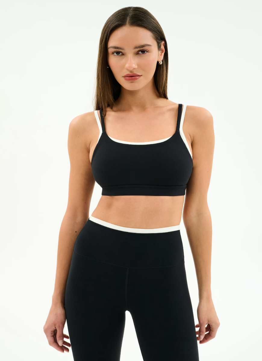 Woman wearing a black sports bra and leggings on a white background