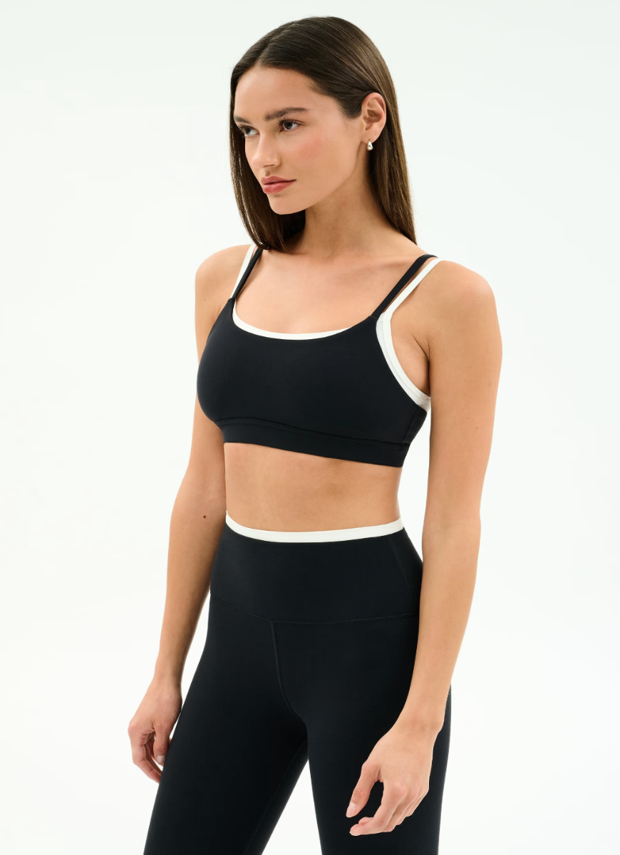 Woman wearing a black sports bra and leggings on a white background