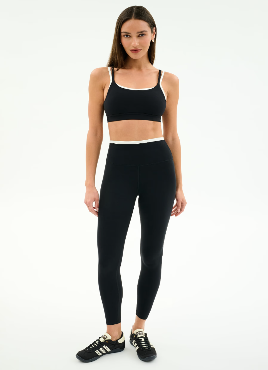 Woman wearing a black sports bra and leggings on a white background