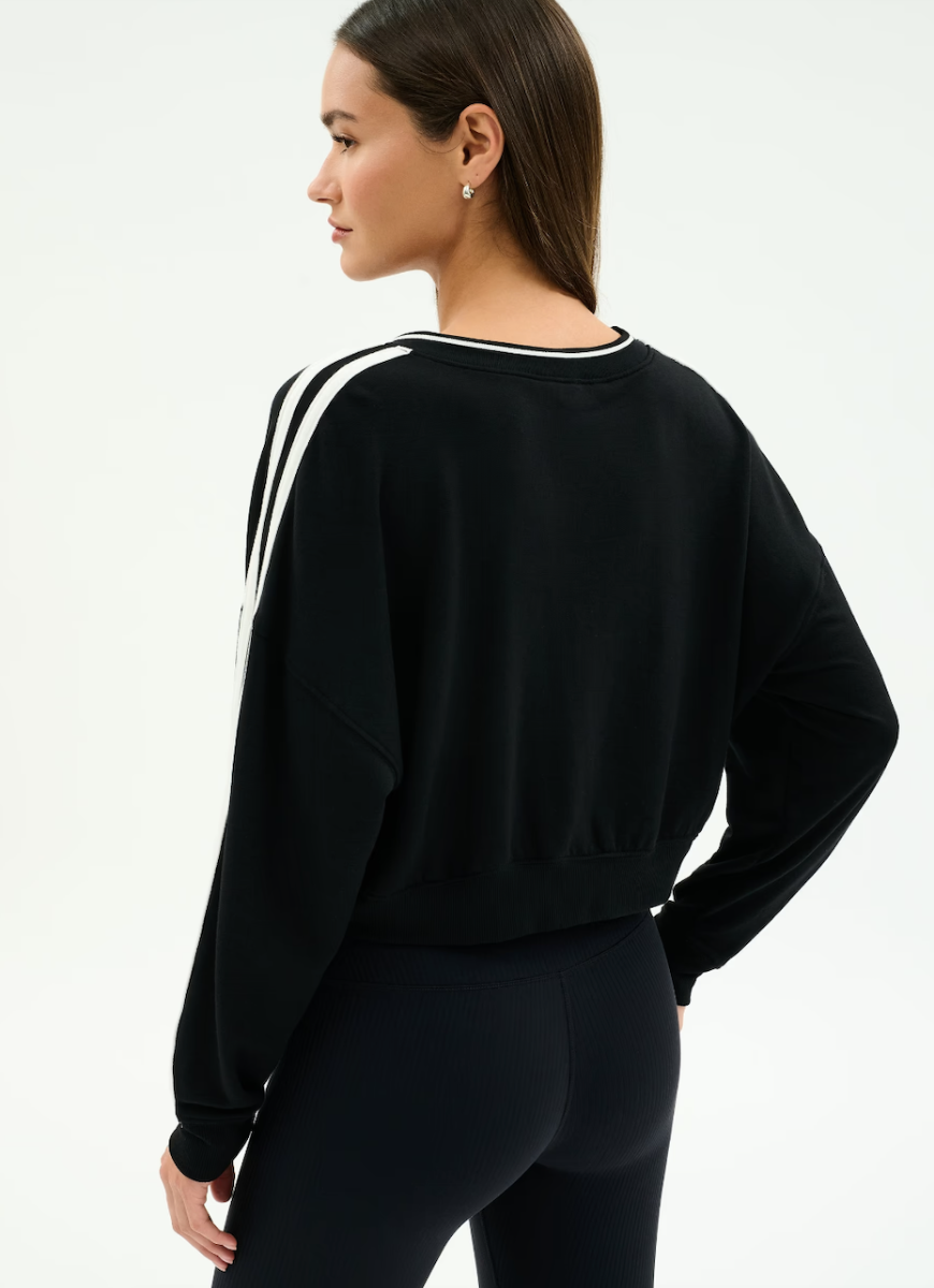 Woman wearing a black sweatshirt with white stripes on a light gray background