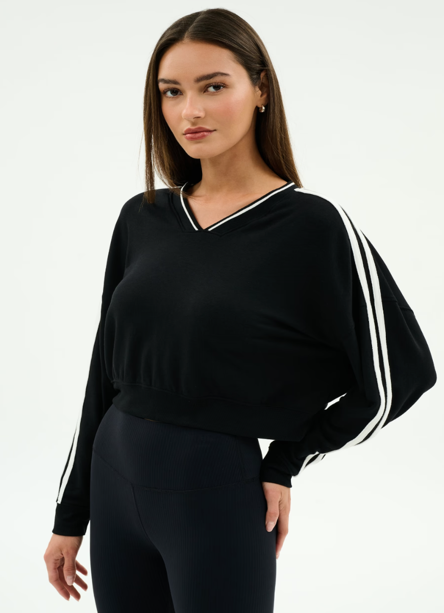 Woman wearing a black outfit with white stripes on a plain background