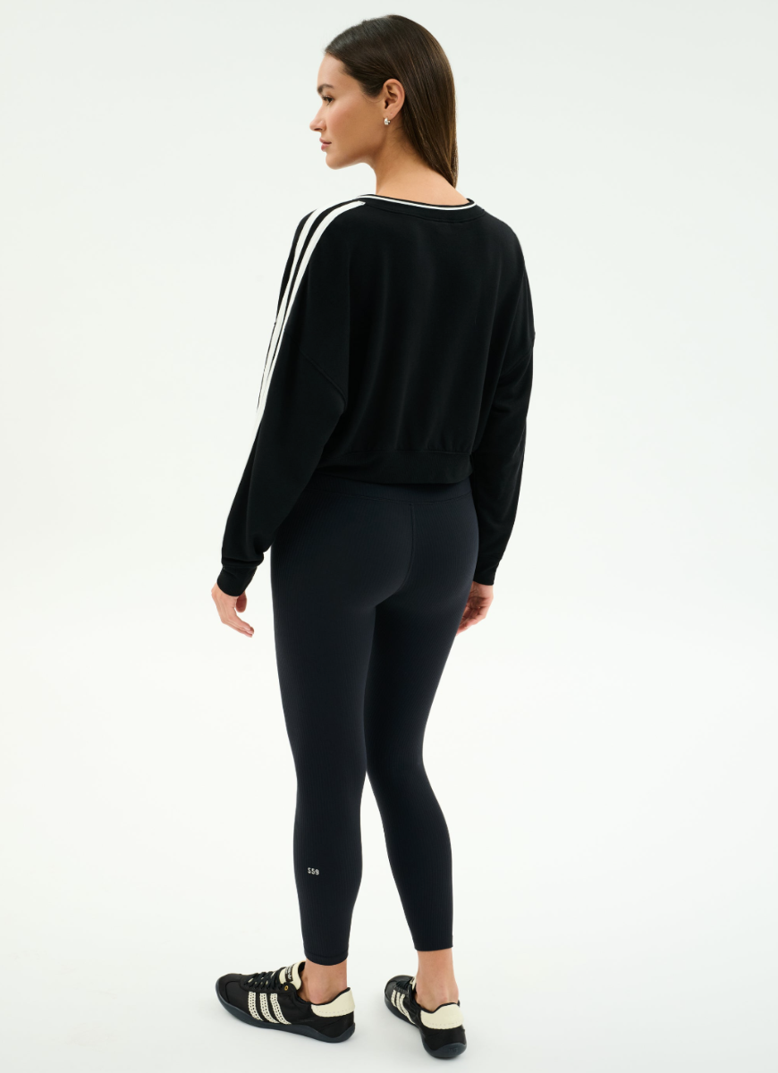 Woman wearing a black tracksuit with white stripes on a white background