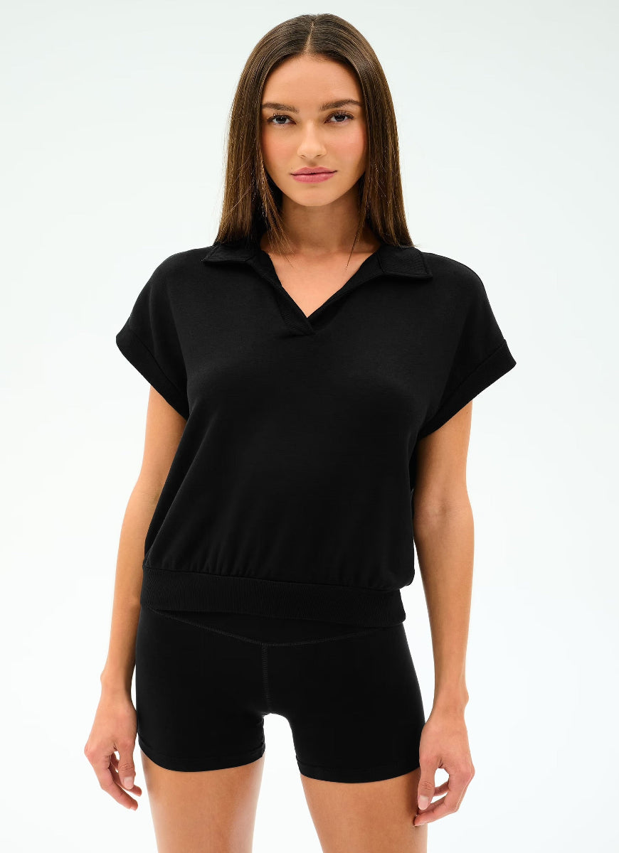 Woman wearing a black polo shirt and shorts on a white background