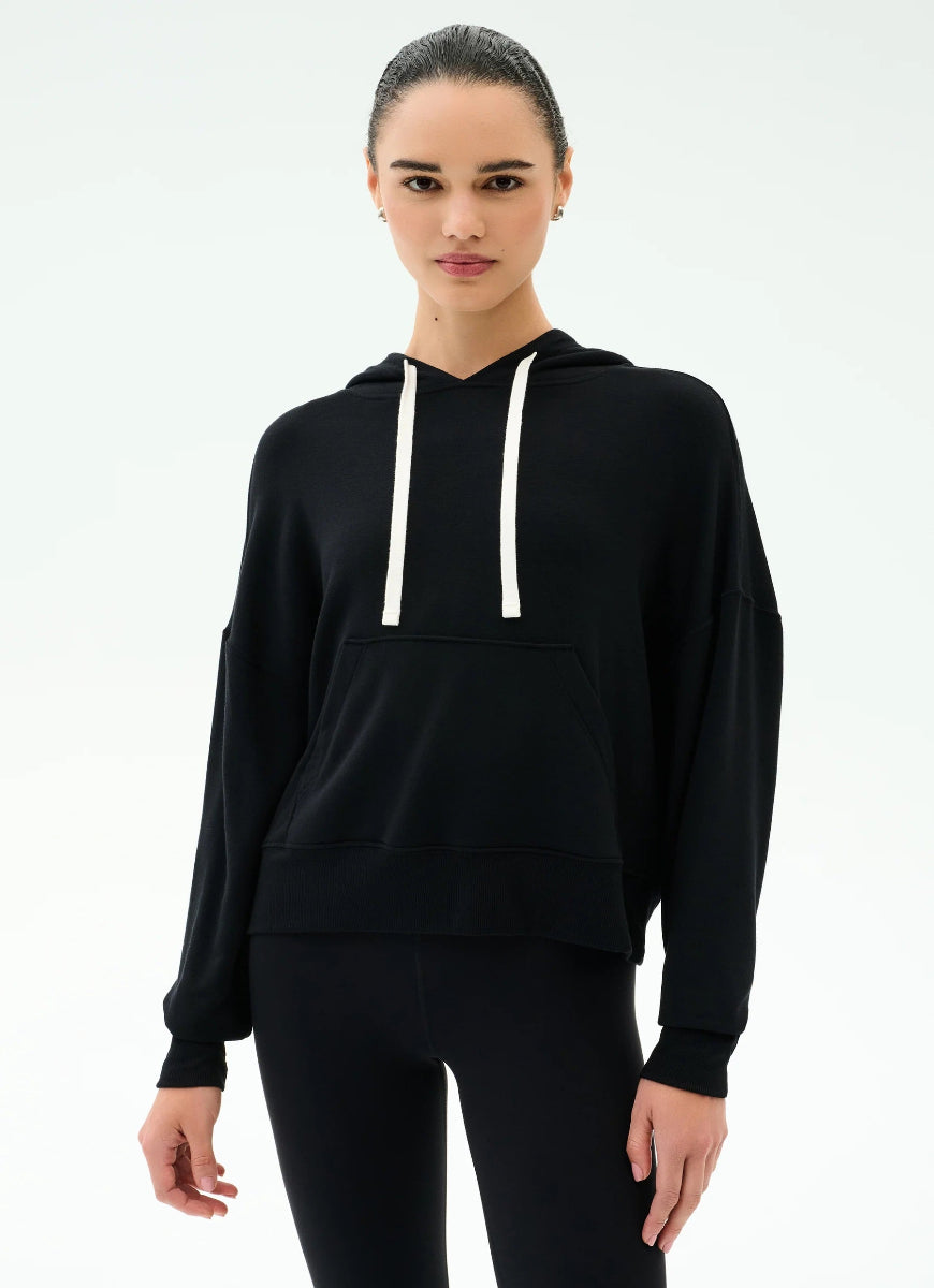 Woman wearing a black hoodie with white drawstrings on a white background