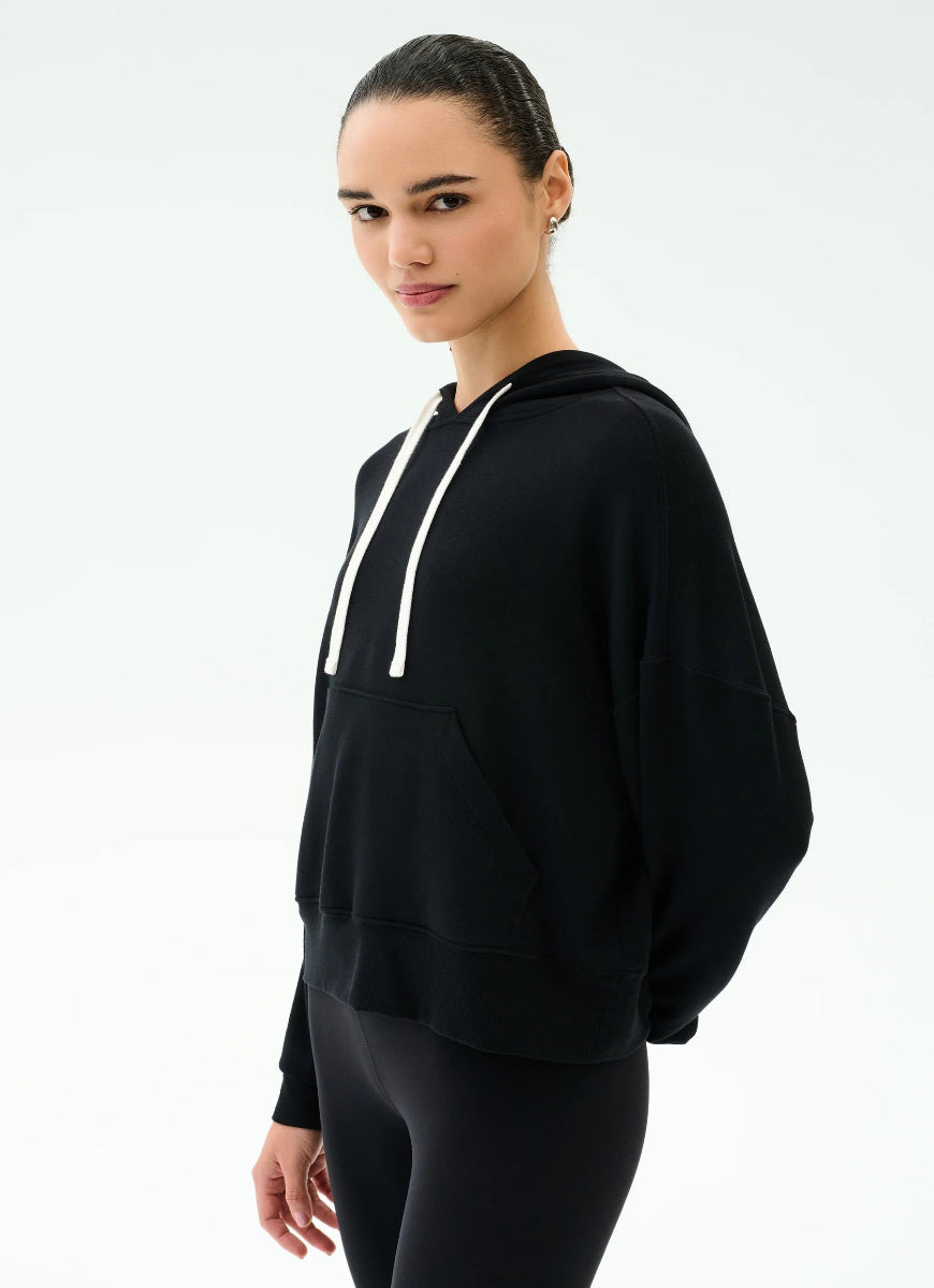 Woman wearing a black hoodie with white drawstrings on a white background