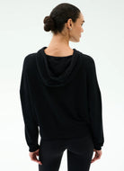 Woman wearing a black hoodie and pants on a white background